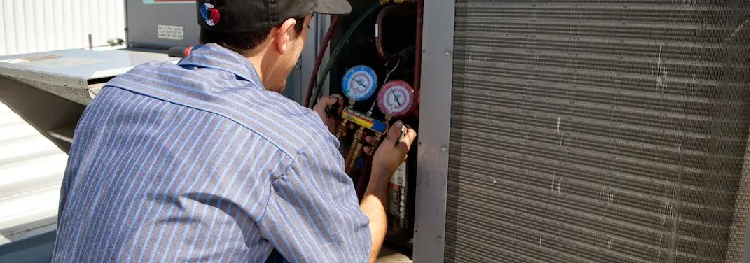 HVAC technician servicing a condenser unit in West Salem