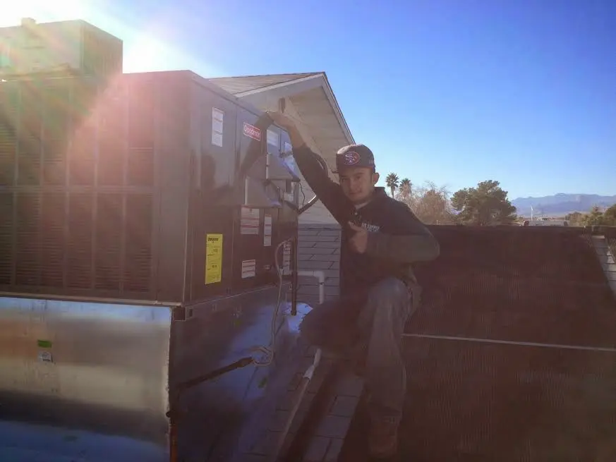 HVAC technician performing Air Duct Cleaning on a rooftop unit in West Salem